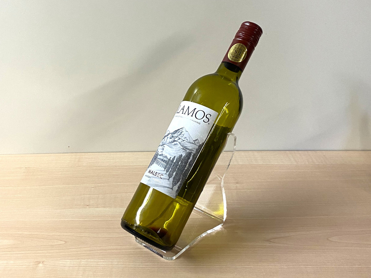 Minimalist home bar or kitchen setup with angled acrylic wine bottle stand in use