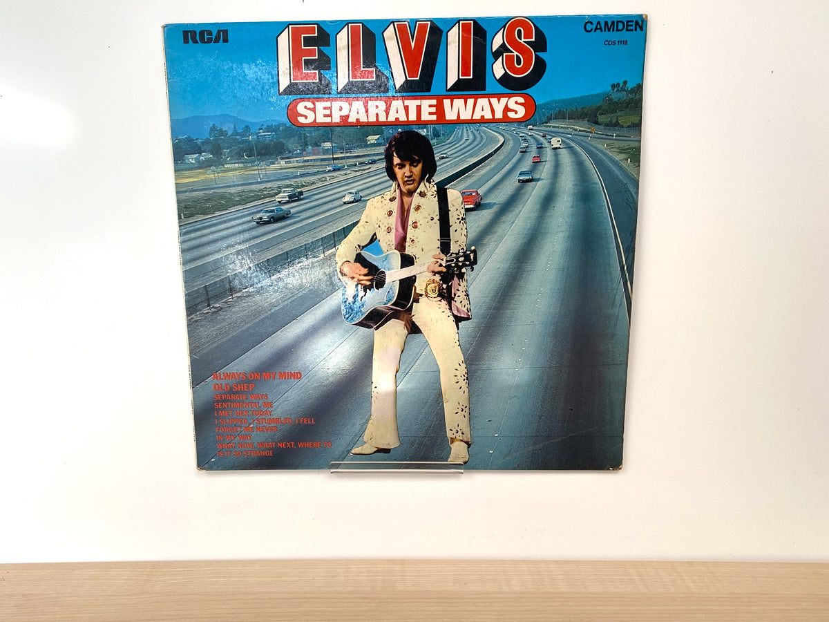 Clear acrylic vinyl LP record holder clip displaying an album against a wall